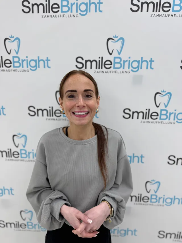 Eine Besucherin lächelt vor der Smile Bright Fotowand.